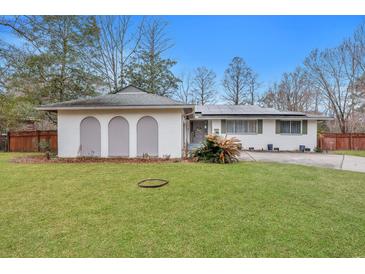 Charming one-story white home featuring a well-maintained lawn and unique architectural details at 1228 Brookside Dr, Hanahan, SC 29410