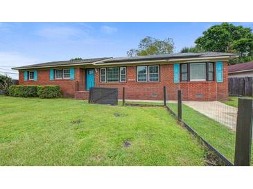 Charming brick home featuring a well-maintained lawn, vibrant blue door, and matching shutters at 1418 Kentwood Circle Cir, Charleston, SC 29412