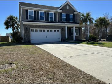 Two-story home featuring a brick facade, attached two-car garage, and a driveway surrounded by trees at 3072 Adventure Way, Ladson, SC 29456