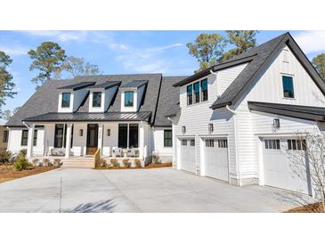 Beautiful two-story home boasts a three-car garage and charming front porch with ample parking on a concrete driveway at 3949 Bulow Landing Rd, Ravenel, SC 29470