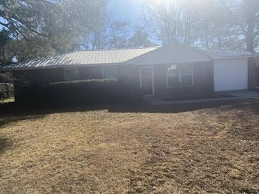 Charming one-story brick home featuring a metal roof and an attached garage at 4793 Popperdam Creek Dr., North Charleston, SC 29418