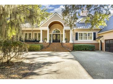 Elegant home with a welcoming front porch, manicured landscaping and spacious driveway at 65 Surfsong Rd, Kiawah Island, SC 29455