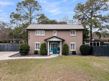 Charming brick two-story home with a metal roof, manicured front yard, and blue front door at 739 Shamrock Ln, Charleston, SC 29412