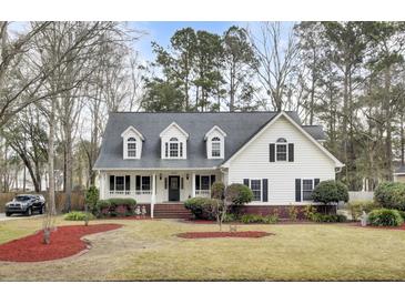 Charming two-story home with a cozy front porch and a well-manicured lawn and landscaped yard at 8656 Laurel Grove Ln, North Charleston, SC 29420