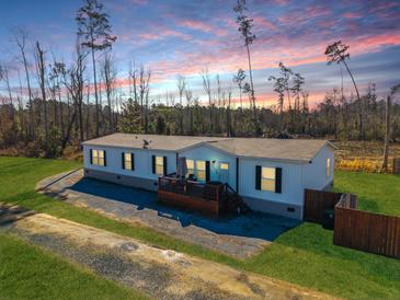Charming single-story home with a cozy front porch, surrounded by a lush green lawn and mature trees at 1026 Cane Gully Rd, Moncks Corner, SC 29461