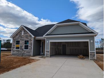 Charming single-story home featuring stone accents and an attached two-car garage with open doors and a large concrete driveway at 119 Palfrey Dr, Ridgeville, SC 29472