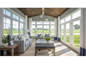 Sunroom boasts large windows, natural light, gray couch, and wood plank ceiling at 4877 Sound View Dr, Mount Pleasant, SC 29466