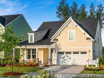 Charming yellow two-story home with a two-car garage, a welcoming front porch, and manicured landscaping at 1332 Homecoming Blvd # Cc2-7-8, Ravenel, SC 29470