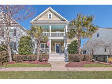 Charming two-story home features a double porch, palm trees, and a well-manicured lawn, with a classic American flag at 2506 Gatewood St, Charleston, SC 29492