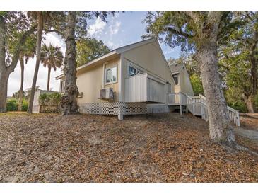 Charming beach house with a raised foundation and inviting stairway entrance surrounded by mature shade trees at 355 Sea Cloud Cir, Edisto Beach, SC 29438