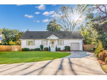 Charming single-story home featuring a manicured lawn, white paint, and attached garage at 704 N Godfrey Park Pl, Charleston, SC 29407