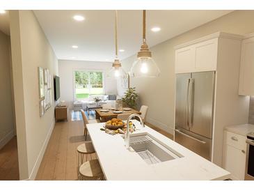 Modern kitchen with stainless steel refrigerator, kitchen island with sink and an open view to the living room at 7614 Indigo Palms Way, Johns Island, SC 29455