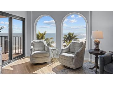 Comfortable living room with two chairs overlooking beach and ocean views from large arched windows at 9002 Palmetto Drive #514 1/13 Share, Isle of Palms, SC 29451
