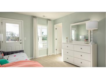 Bright bedroom features a bed, dresser with mirror, and access to the outdoors at 546 Richfield Way, Summerville, SC 29486