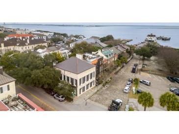 An aerial view of a stately two-story home near the water, featuring dark shutters and cobblestone streets at 90 E Bay St, Charleston, SC 29401
