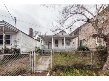 Exterior shot of home with covered porch, fenced front yard, and adjacent houses at 355 Nassau St, Charleston, SC 29403