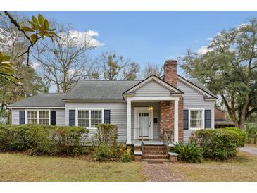 Charming single-story home with gray siding, brick chimney, manicured landscaping, and inviting front porch at 105 S Palmetto St, Summerville, SC 29483