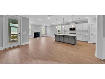 Open-concept living area featuring a fireplace, modern kitchen island, and access to an outdoor patio at 782 Blueway Ave, Summerville, SC 29486