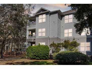 Three-story condominium with gray siding, balconies, manicured bushes, and a well-maintained lawn at 700 Daniel Ellis Dr # 5302, Charleston, SC 29412