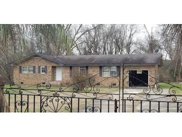 Charming brick home features an attached garage and a decorative wrought iron fence, with mature trees surrounding the property at 1097 Murrell Block Dr, Pineville, SC 29468