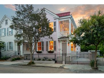 Charming two-story home featuring a wrought iron fence, second story porch, and a beautifully landscaped yard at 12 Percy St, Charleston, SC 29403