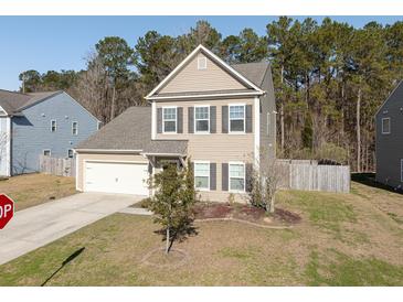 Charming two-story home with a manicured front yard and attached garage. The house has neutral siding and dark shutters at 122 Rockingham Way, Moncks Corner, SC 29461