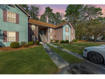 Inviting condo complex featuring a covered stairwell entrance, green lawn and convenient parking at 7930 Timbercreek Ln # C, North Charleston, SC 29418