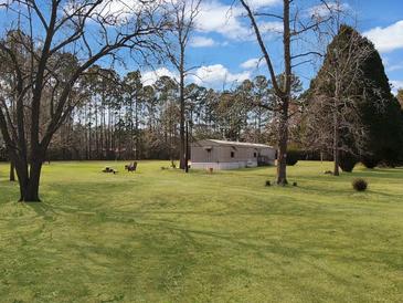 A charming home surrounded by a lush green lawn and mature trees, creating a serene and private setting at 835 Gross Ave, Moncks Corner, SC 29461