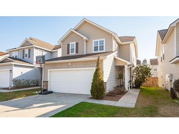 Two-story home with a two-car garage, a basketball hoop, and manicured landscaping at 8816 Kellum Dr, North Charleston, SC 29420