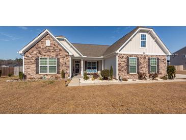 Charming single-story home featuring a stone facade, landscaped front yard, and covered porch at 121 Lakelyn Rd, Moncks Corner, SC 29461