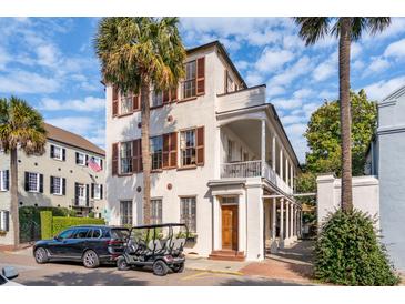 Stately multi-story home showcasing a beautiful facade, private golf cart, mature palm trees, and a blue sky backdrop at 38 State St # 2, Charleston, SC 29401