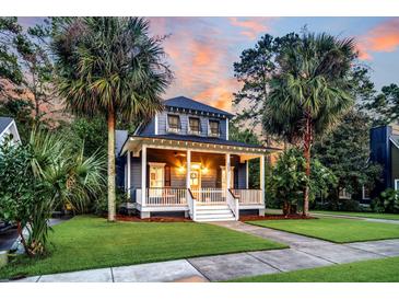 Charming two-story home with a welcoming front porch, lush lawn, and beautiful palm trees at sunset at 4057 E Amy Ln, Johns Island, SC 29455