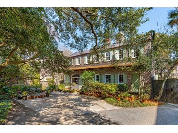 Charming two-story brick home featuring lush greenery, traditional shutters, and a spacious gravel driveway at 42 Barre St, Charleston, SC 29401