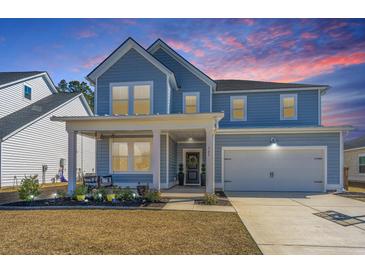 Charming two-story home showcasing a well-manicured front yard and an inviting covered porch at 143 Oyster Tide Ave, Summerville, SC 29485