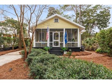 Charming cottage-style home featuring a screened porch and beautifully landscaped front yard with brick walkway at 221 Church St, Mount Pleasant, SC 29464