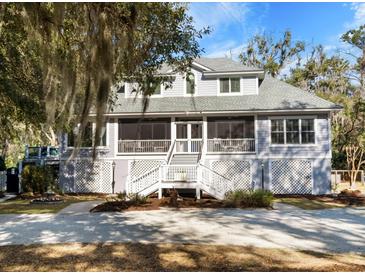Two-story home featuring a large porch and landscaped front yard on a sunny day at 8834 Palmetto Rd, Edisto Island, SC 29438