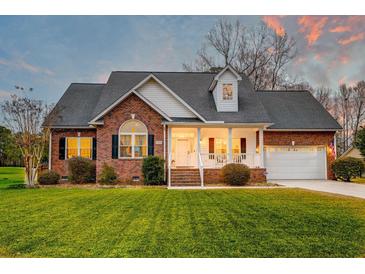 Charming brick home features a well-manicured lawn, inviting front porch, and attached two-car garage at 1006 Retreat Ave, Moncks Corner, SC 29461