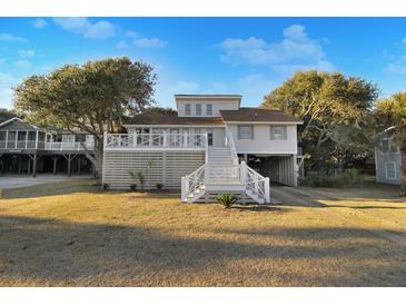Charming coastal home with a white exterior, elevated design, and beautiful landscaping on a sunny day at 707 Palmetto Blvd, Edisto Island, SC 29438