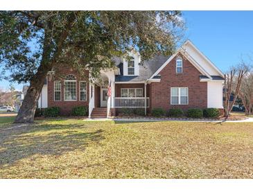Charming brick home with a front porch and well-maintained lawn on a sunny day at 8696 Spring Chapel Ln, North Charleston, SC 29420