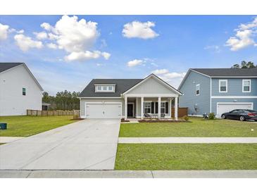 Charming single-story home with a well-manicured lawn and welcoming front porch seating at 127 Oyster Tide Ave, Summerville, SC 29485