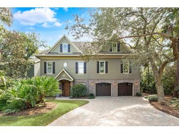 Charming home with a two-car garage, brick accents, and mature landscaping at 176 Marsh Hawk Ln, Kiawah Island, SC 29455