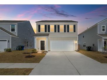 Two-story home featuring a two-car garage and neutral siding, set against a vibrant sunset sky at 4368 Ocean Farm Dr, Summerville, SC 29485