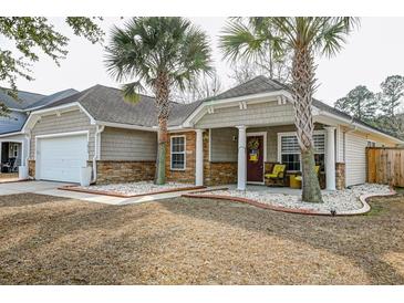 Inviting single story home featuring stone accents, manicured lawn, and a cozy covered front porch at 7034 Lanier St, Hanahan, SC 29410