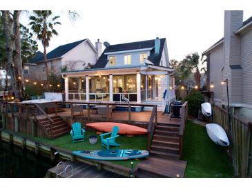 Stunning backyard featuring a wooden deck, lush green grass, outdoor furniture, and water access at 810 Harbor Place Dr, Charleston, SC 29412
