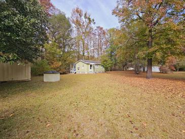 Quaint cottage-style home featuring a lush front lawn with mature trees and a welcoming entrance, perfect for outdoor enjoyment at 3695 Cannon Rd, Round O, SC 29474
