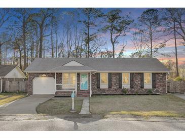 Charming brick home with an attached garage, a well-maintained lawn and a bright blue front door at 105 Alan Ct, Summerville, SC 29485
