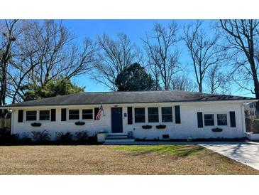 Charming single-story home with white brick, black shutters, flower boxes and an American flag flying by the front door at 2137 Barbour Dr, Charleston, SC 29414