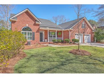 Beautiful brick home with a well-manicured lawn, inviting front porch, and a two-car garage at 8757 E Fairway Woods Dr, North Charleston, SC 29420