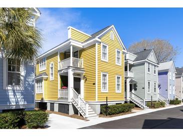Charming yellow two-story home with double balconies and manicured landscaping, set under a clear blue sky at 108 Smith St # 108-C, Charleston, SC 29403