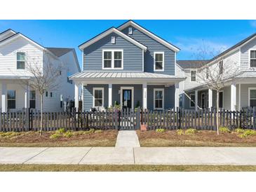 Charming blue two-story home with a covered porch and black picket fence under a bright blue sky at 1368 Clay Field Trl, Summerville, SC 29485